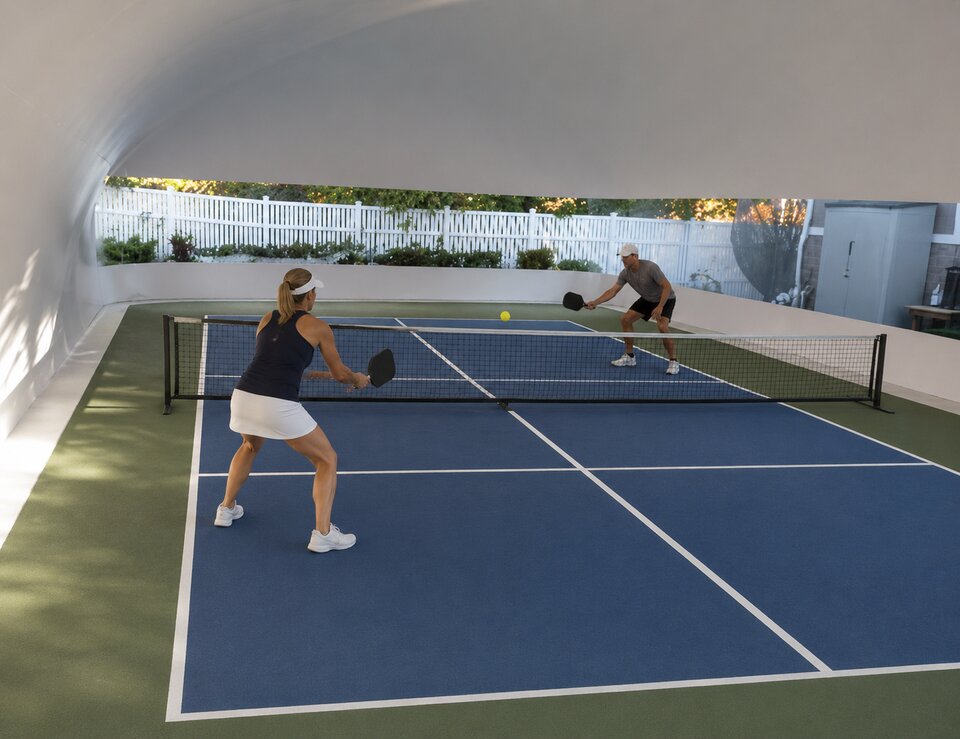 Players using an indoor pickleball court under a dome cover