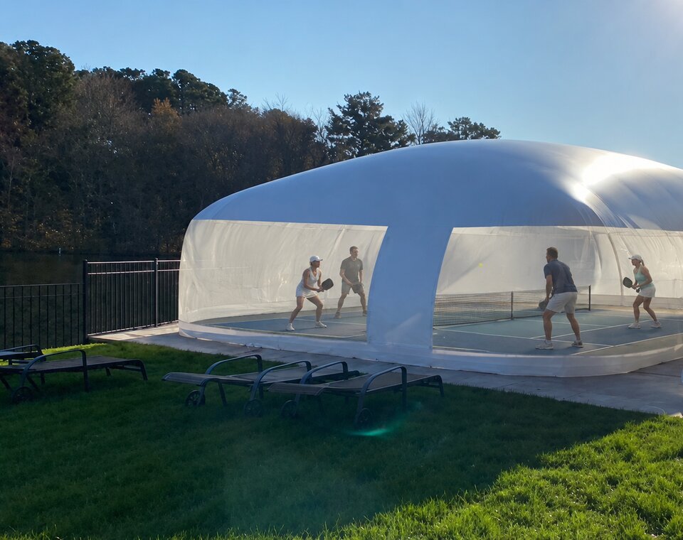Players using a private pickleball court inside a white air-supported dome