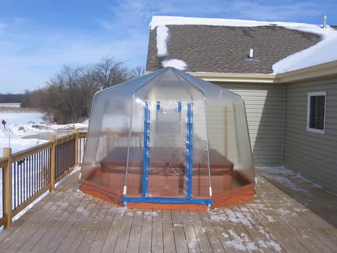 Clear vinyl Fabrico spa enclosure with a zippered doorway over a hot tub on a wood deck
