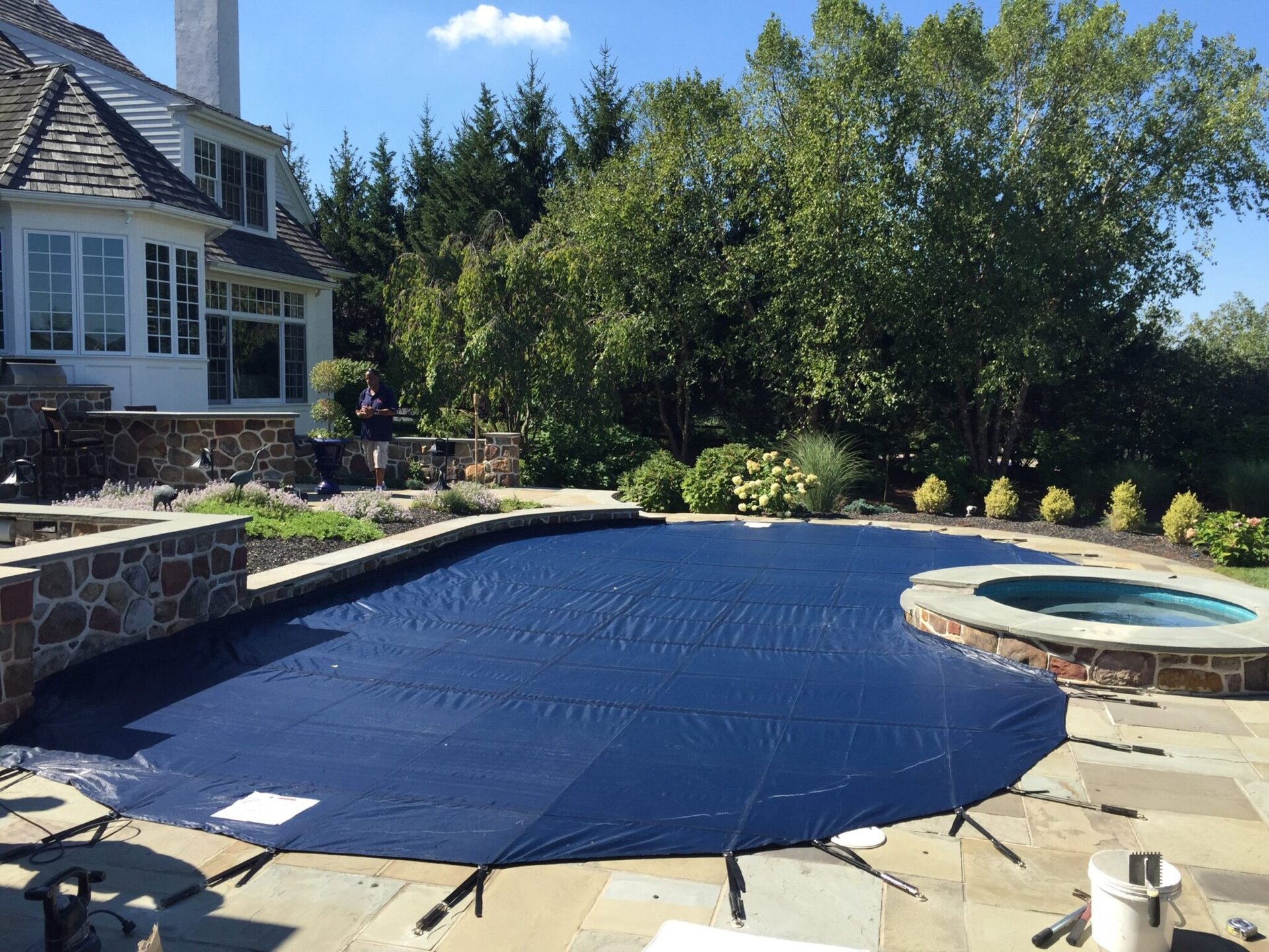 Blue Anchor Defender Mesh safety cover fitted around a raised spa on a residential pool