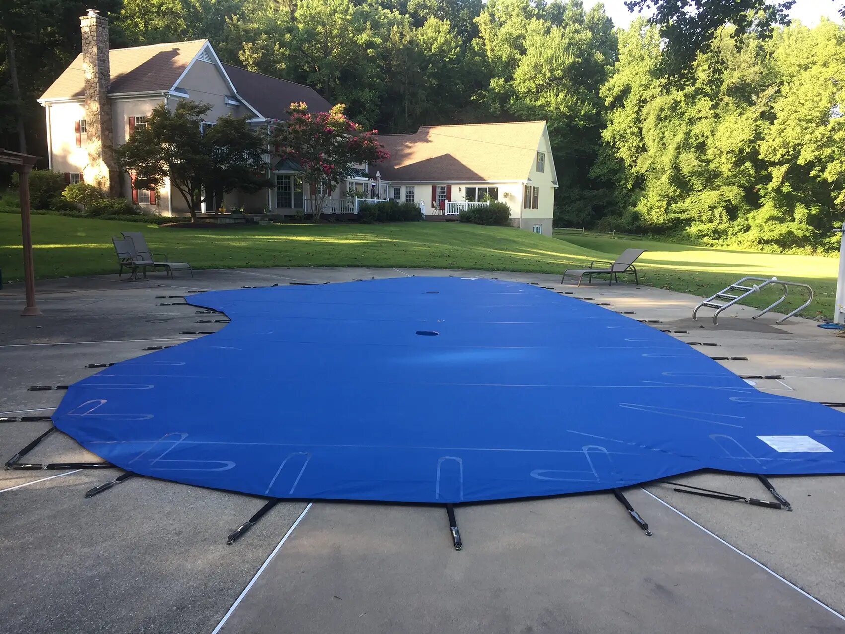 Blue Anchor Cross Star solid safety cover installed over a residential pool
