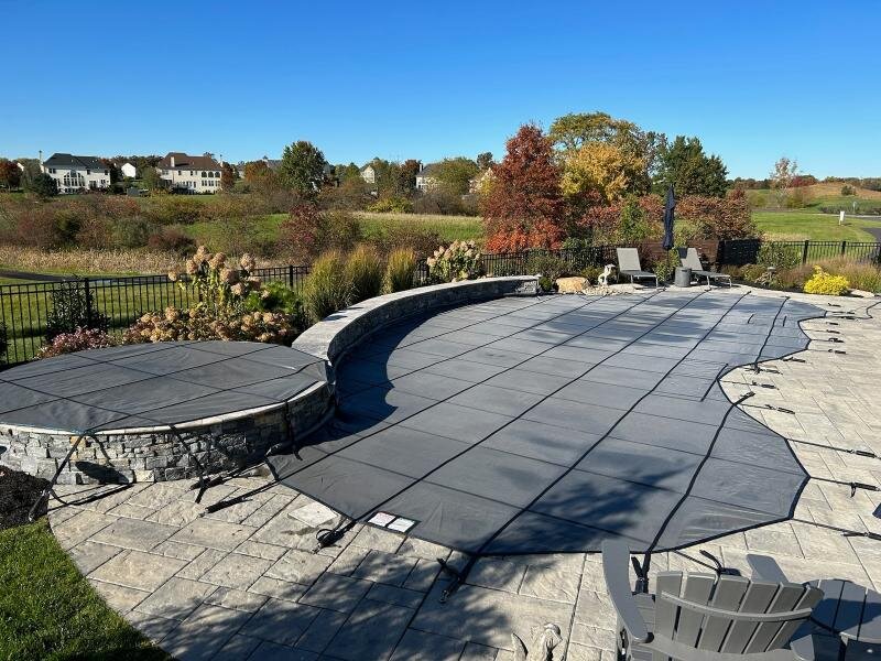 Gray Super Coverlon Mesh safety cover fitted around a curved pool and raised stone spa
