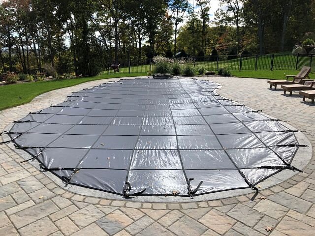 Gray Latham solid safety cover installed over a curved residential pool
