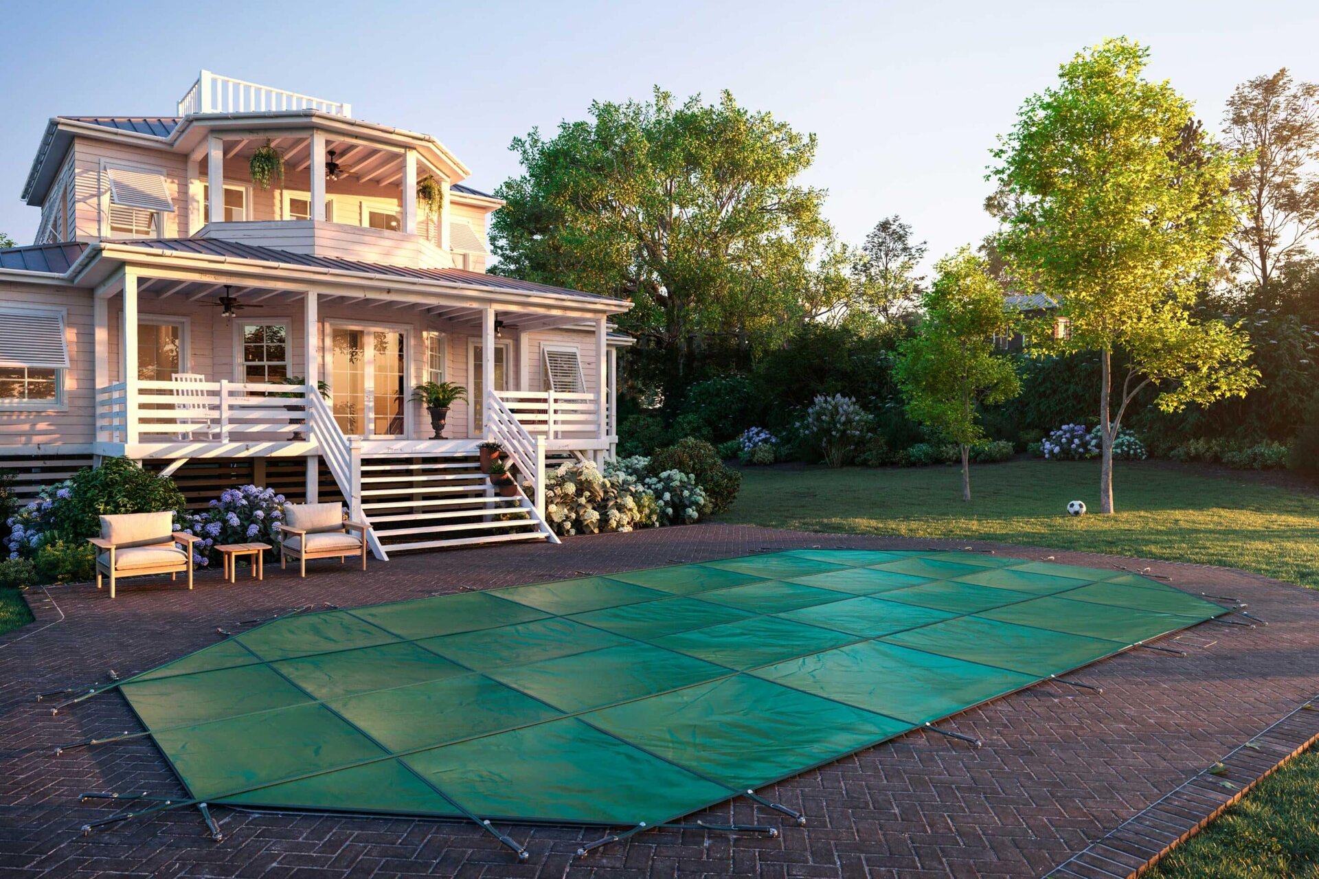 Green Latham winter safety cover installed over a pool beside a home