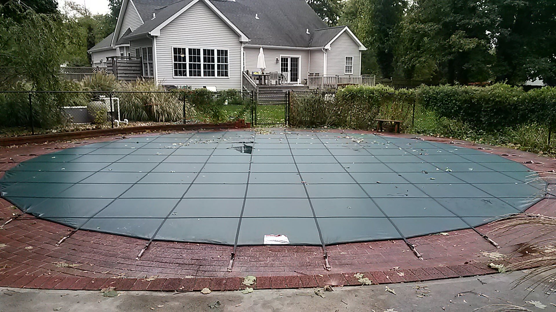 Green Merlin SmartMesh cover secured around a backyard pool
