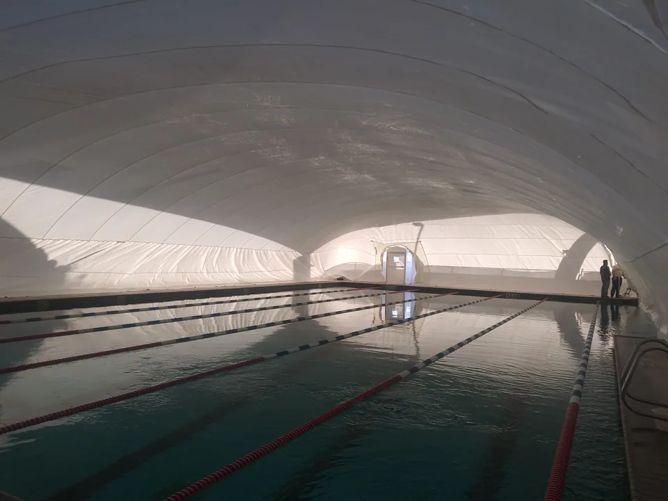 Lap pool with lane lines and surrounding deck inside a white commercial Ameri-Dome
