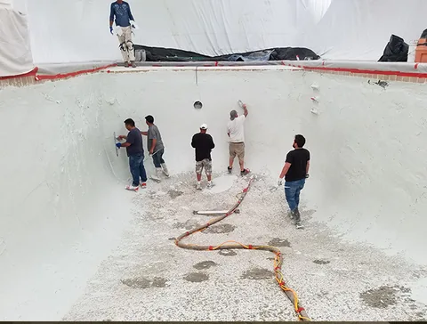 Workers finishing the pool walls beneath the enclosure