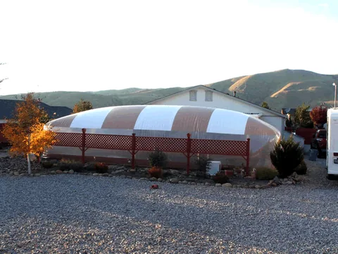 Tan and white striped pool dome behind a lattice fence in a desert yard