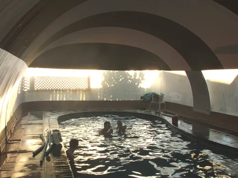 Backlit interior of a striped pool dome with several swimmers in the pool