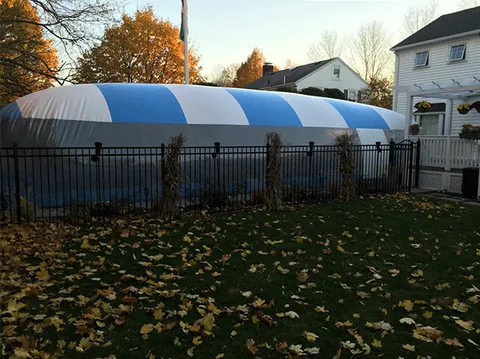 Side view of a blue and white striped pool dome behind a black fence