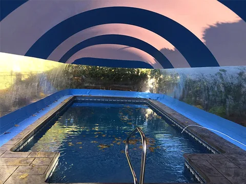 Daytime interior of a rectangular pool beneath a blue and white striped dome