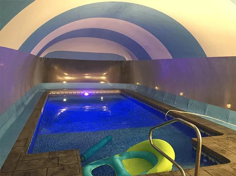 Illuminated pool and floats inside a blue and white striped dome at night