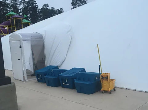 Airlock entry and equipment beside a white commercial pool dome