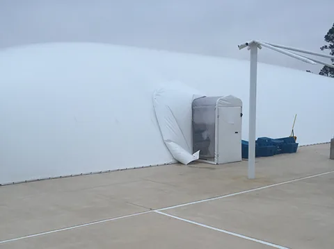 Wide exterior view of a white commercial pool dome and airlock