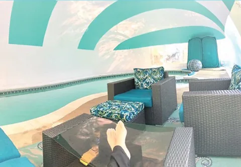 Lounge chairs and seating beside a pool beneath an aqua and white dome