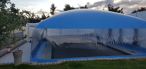 Blue and clear pool dome enclosing a raised pool