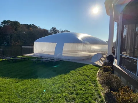 Blue and white pool dome beside a Delaware home