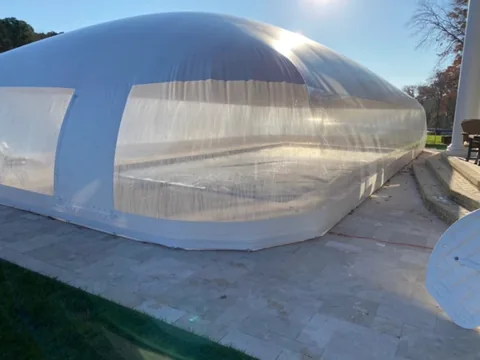 Close exterior view of a blue and white pool dome on a stone deck