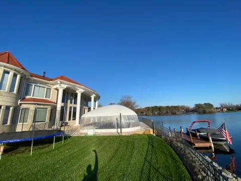 Pool dome beside a lakeside home viewed from the lawn