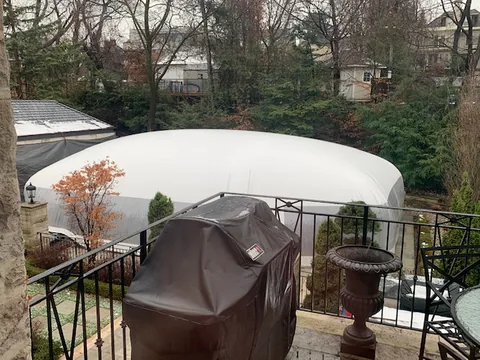 White free-form pool dome exterior viewed across a patio