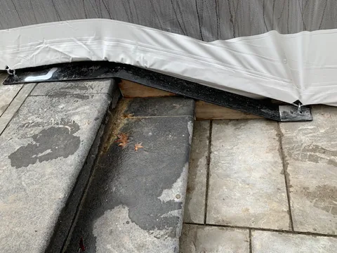 Close view of the pool dome ballast edge secured along a stone deck