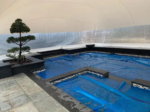 Covered free-form pool and stone deck inside the dome
