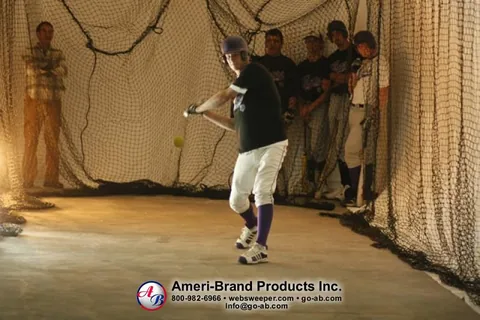 Baseball player taking batting practice inside a netted inflatable pitching dome