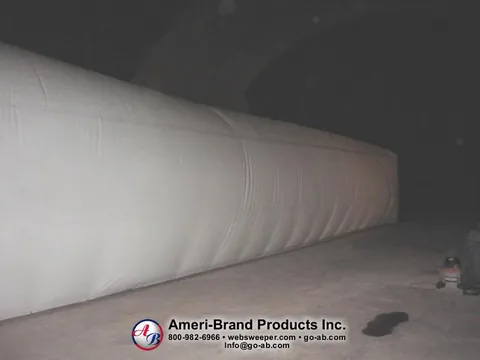 Side view of a long white inflatable pitching dome inside a dark Sport Dome