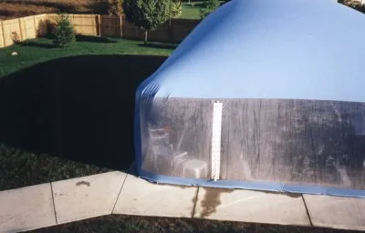 Clear end wall and entry of an aqua pool dome beside a patio
