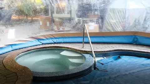Water-tube pool dome enclosing an inground pool and spa
