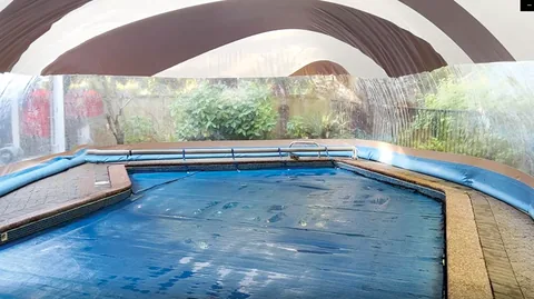 Inground pool enclosed by a striped water-tube dome