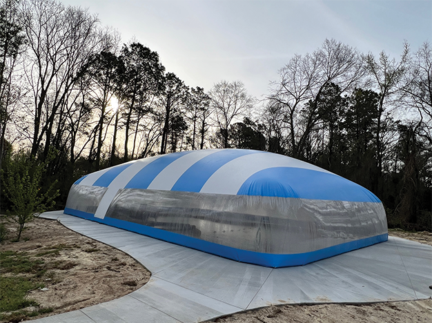 Residential Ameri-Dome with a blue-and-white striped roof and clear walls enclosing a backyard pool