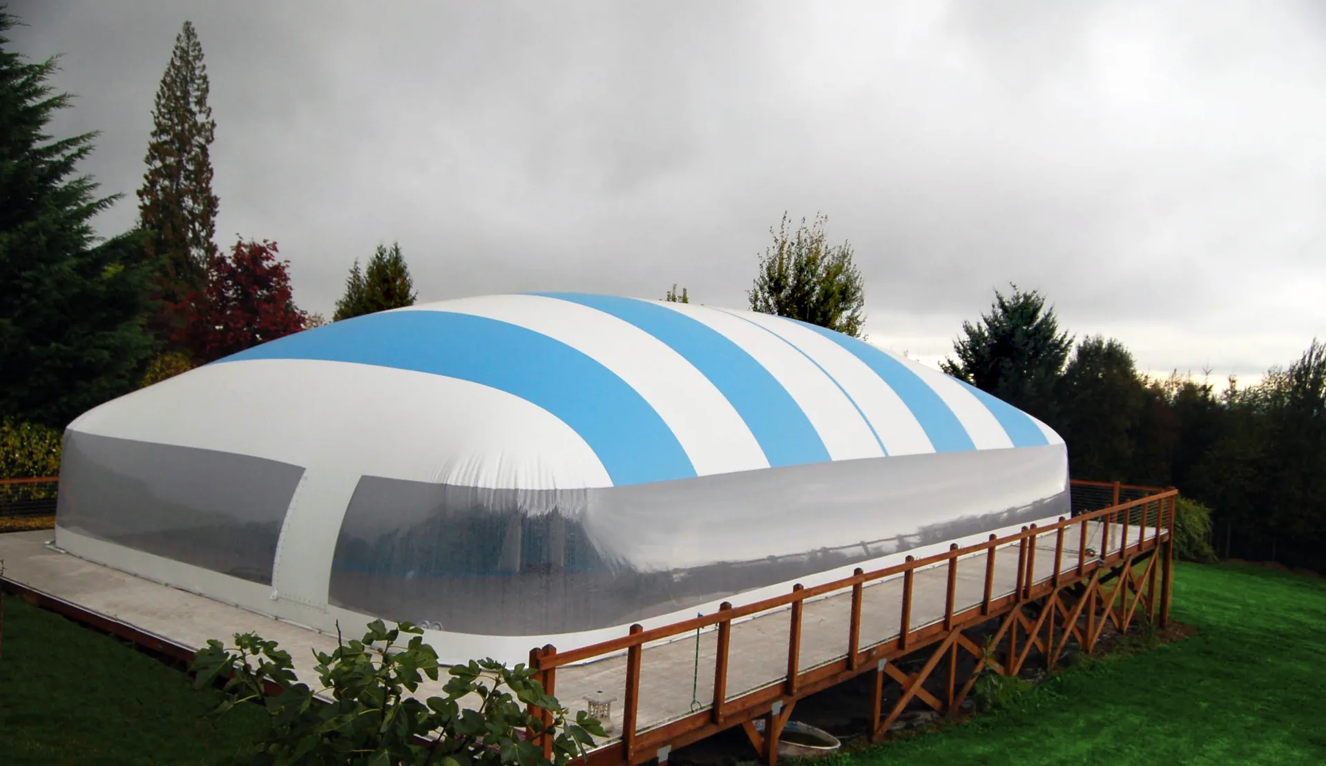 Blue-and-white residential Ameri-Dome installed over an elevated pool deck