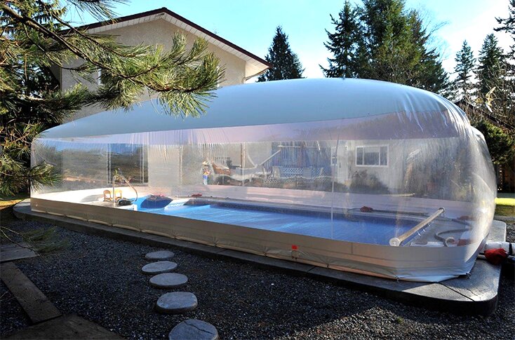 Clear residential Ameri-Dome enclosing a backyard pool beside a home