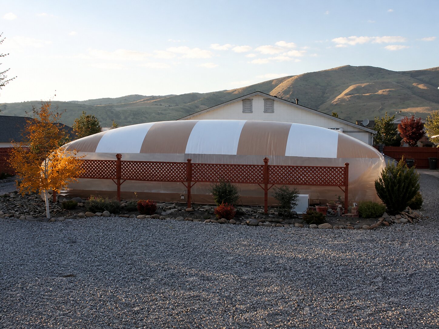 Tan-and-white residential Ameri-Dome behind a lattice fence in a mountain yard