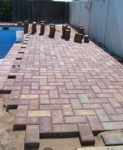 Picture shows remaking of deck. Pavers installed along perimeter of pool to clean up appearance of pool deck.