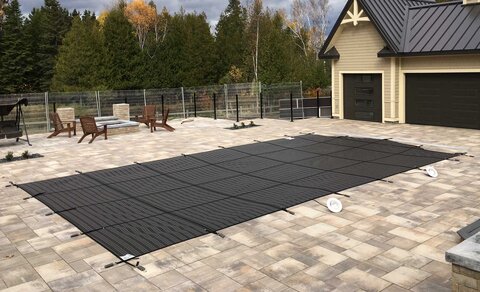 Mesh safety pool cover secured by straps to deck anchors