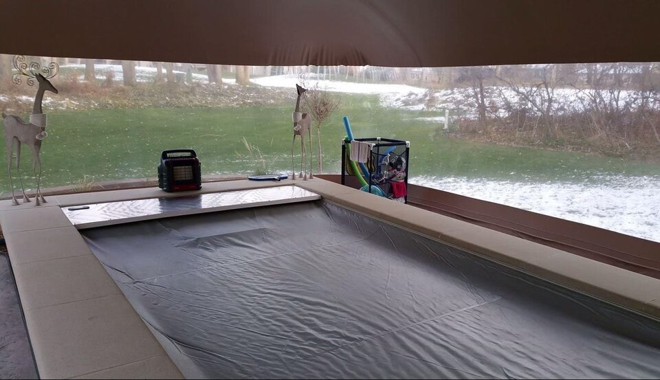 Covered swim spa inside the enclosure with the snowy yard visible through the clear vinyl walls